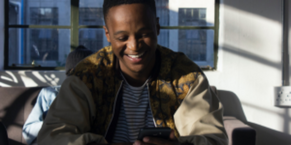 Smiling man in city apartment looking at his mobile phone